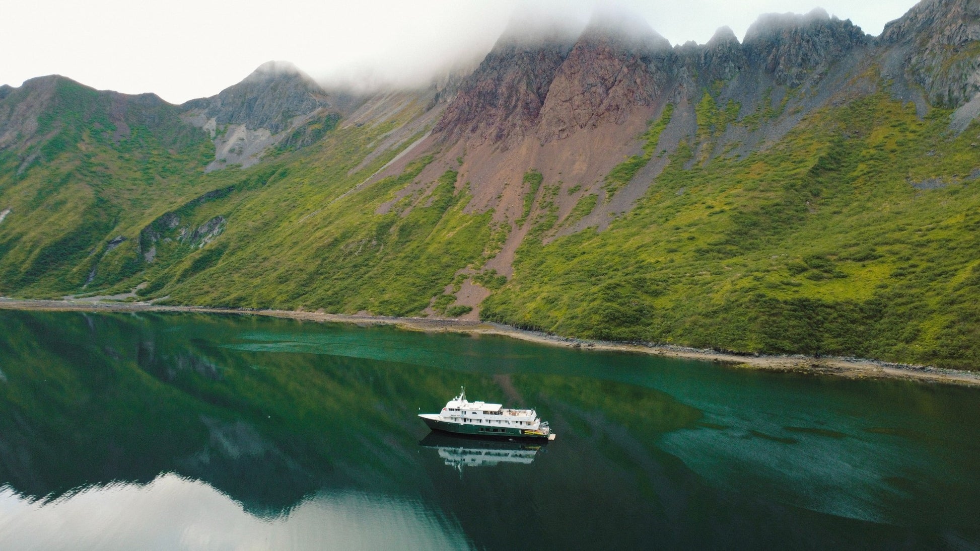 Ship in front of tall mountains in the Aleutian Islands