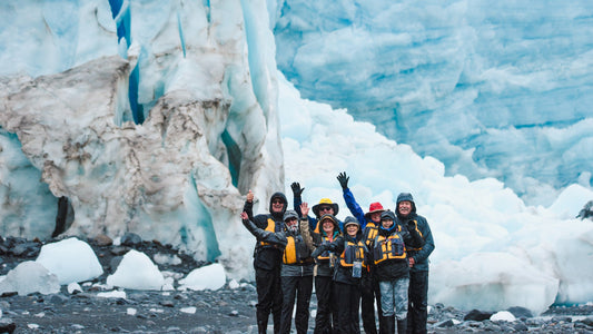 Group of people wearing PFDs standing in front of a large glacier-UnCruise Adventures 